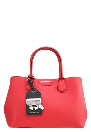 Sac à main rouge Karl Lagerfeld avec une étiquette noire et blanche à l'effigie de Karl Lagerfeld attachée à une des poignées.
