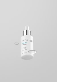 Witte serumfles met een zilveren druppelkap. Etiket leest "TIRTIR PHA 15% SERUM" met details over ingrediënten en volume, 30 ml.