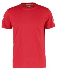Camiseta roja de manga corta con cuello redondo, con un parche de la bandera estadounidense en la manga derecha y un parche de emblema de estrella en la manga izquierda.