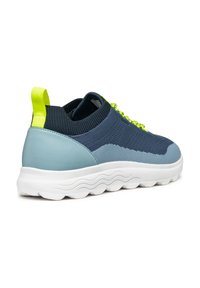 Sneaker navy e azzurro chiaro con una tomaia in maglia testurizzata, dettagli delle lace in giallo neon e una suola bianca ondulata; presenta una linguetta sul retro.