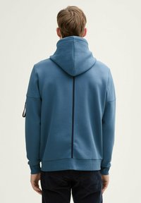 Bluza z kapturem z bawełny, z plisą na plecach i boczną kieszenią na zamek. Gładka faktura, ribbowe mankiety i dół.