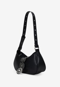 Bolso de mano de cuero negro con forma curva, correa adornada con tachuelas y acentos decorativos en tono plateado. Cuenta con un cierre de cremallera y detalle texturizado en la correa.