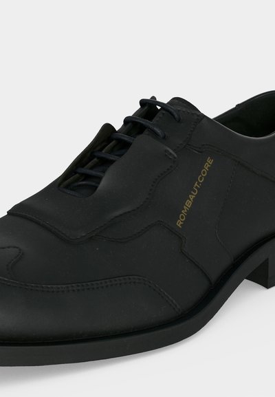 Μαύρο δερμάτινο παπούτσι με κορδόνια μπροστά, ραφές, χαμηλό τακούνι και χρυσό λογότυπο "ROMBAUT-CORE" στο πλάι.