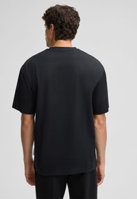 Schwarzes T-Shirt mit kurzen Ärmeln und lässiger Passform, aus weichem Stoff gefertigt, mit rundem Halsausschnitt und ohne sichtbare Grafiken oder Muster.