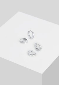 Ensemble de quatre boucles d'oreilles créoles en argent avec des designs variés : deux lisses et deux avec des accents de pierres précieuses transparentes. Différentes tailles et épaisseurs.