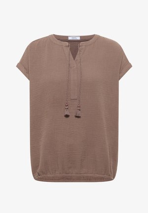 Blouse texturée marron clair à manches courtes avec encolure ronde, fente devant et liens décoratifs à pompons, présentant une coupe décontractée et des manches retroussées.