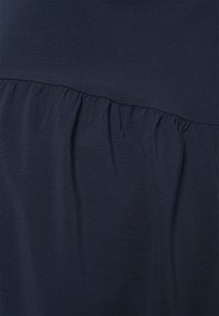 Vestido azul-marinho com uma parte superior lisa e tecido franzido na cintura, criando uma silhueta descontraída. Material suave e elástico.