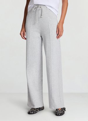 Pantaloni della tuta grigio chiaro a gamba larga, realizzati in tessuto morbido ed elastico, con vita regolabile con coulisse, cuciture laterali e silhouette coordinata.