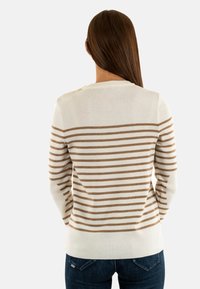 Pull crème avec des rayures horizontales marron, manches longues et col rond. Le matériau semble doux avec une texture lisse.