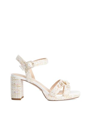 Sandale blanche en tweed à talon bloc avec bride à la cheville à boucle et perles décoratives ainsi que des ornements dorés sur les brides avant.