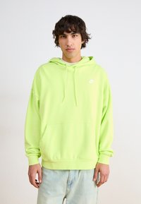Neon zelená mikina s kangaroo vreckom, kapucňou na šnúrku a bielym logom. Voľný strih s rebrovanými manžetami a spodným lemom. Materiál prispôsobený na pranie v práčke.