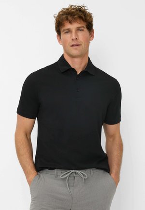 Black short-sleeve polo shirt with a soft texture, button placket, and a collar; paired with light gray drawstring pants.