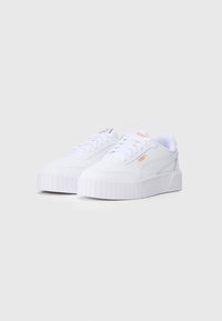 Adidași albi cu un superior din pânză texturată, șireturi plate și o talpă din cauciuc groasă, cu zimți. Prezintă un accent subtil al logo-ului în aur.
