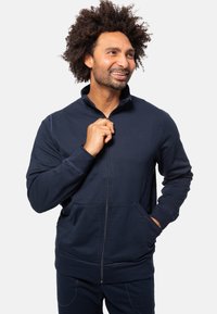 Granatowy hoodie na zamek błyskawiczny z wysokim kołnierzem, przednimi kieszeniami i gładką teksturą. Idealny na codzienne wyjścia, zapewniający dopasowane ubranie.