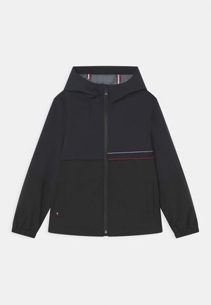 Chaqueta con capucha y cremallera en negro y azul marino oscuro, con puños elásticos, dos bolsillos delanteros y una delgada franja horizontal roja y blanca a lo largo del pecho.