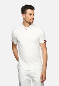 Witte polo met korte mouwen, voorzien van een drieknoopsluiting, rode en donkerblauwe accenten op de manchetten, en een gestructureerde stof.