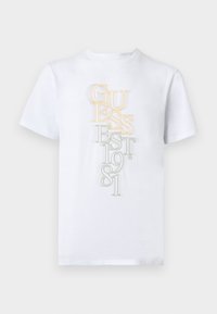 Λευκό κοντομάνικο T-shirt με κάθετο, επικαλυπτόμενο κείμενο "GUESS EST. 1981" σε κίτρινο και γκρι στο κέντρο μπροστά.