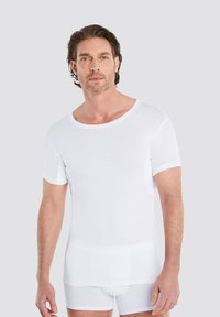 White crew-neck t-shirt made of soft fabric, short sleeves, and a relaxed fit, paired with white shorts. Simple design, no patterns.