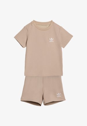 Conjunto beige de dos piezas que incluye una camiseta de manga corta y textura, y pantalones cortos a juego, ambos con un pequeño logo blanco de adidas.
