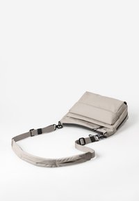 Lichtgrijze schoudertas met verstelbare strap, voorste ritszak en een gepolsterd voor gedeelte, plat gelegd op een witte achtergrond.