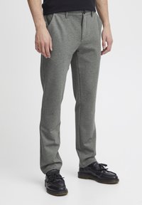 Pantalones grises con textura y corte recto, que cuentan con bolsillos y cierre de botón, combinados con zapatos negros de cordones.