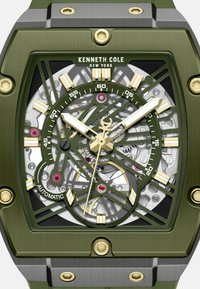 Grüne rechteckige Uhr mit einem transparenten Skelettdesign, goldenen Akzenten und silbernen Details. Verfügt über goldene und schwarze Marker sowie Zeiger.