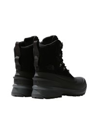 Bottes noires imperméables avec une tige haute, en tissu texturé et matériaux synthétiques, dotées d'une semelle épaisse et de coques de protection en caoutchouc renforcé.