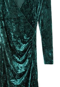 Abito di velluto verde scuro con maniche lunghe, design avvolgente e dettagli drappeggiati su un lato. Tessuto morbido con una finitura lucida e liscia.