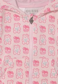 Felpa con zip rosa caratterizzata da un motivo con orsetti e barattoli di miele, texture in tessuto morbido e zip silver con un accento triangolare.