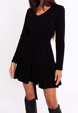 Černé dlouhé šaty s dlouhým rukávem a výstřihem do V, se stáhnutým pasem a volánkovým lemem. Vyrobené z měkkého materiálu, obsahují zavazovací pás pro úpravu střihu.