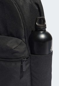 Μαύρη τσέπη σακιδίου πλάτης με μια μαύρη μπίλια νερού. Το σακίδιο διαθέτει υφή νάιλον και λεπτομέρεια με φερμουάρ, με το λογότυπο στο κρεμαστό φερμουάρ.