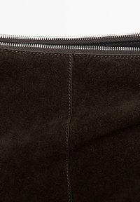 Borsa in camoscio marrone con texture liscia, linee pulite e chiusura con zip argentata sulla parte superiore. Dettaglio di cuciture minime sulla superficie.