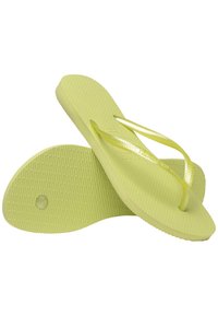 Des tongs jaunes avec des semelles texturées et des fines lanières. Les semelles sont rondes avec un petit trou et une surface à motifs pour une meilleure adhérence.