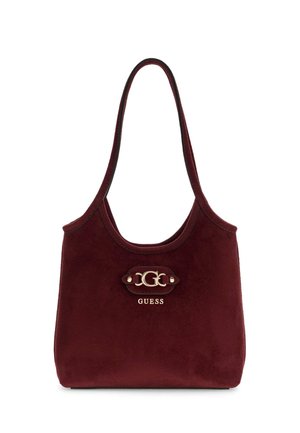 Burgundy suede shoulder bag with long strap, gold GUESS logo plaque in center on front.