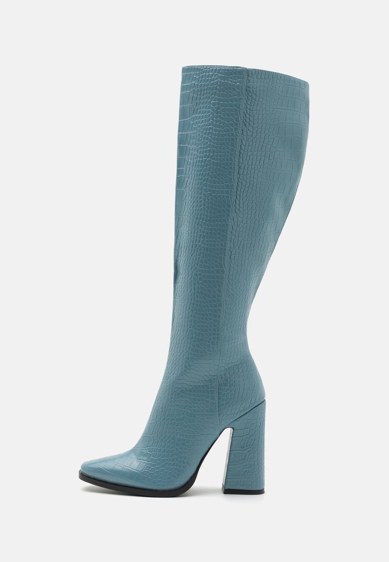 Botte haute bleue jusqu'au genou avec texture crocodile, bout pointu et talon haut épais sur fond blanc.