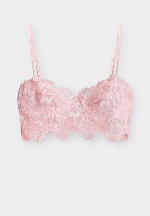 Απαλό ροζ δαντελένιο σουτιέν bralette με λουλουδένια σχέδια και ρυθμιζόμενες λεπτές τιράντες σε απλό ανοιχτό φόντο.