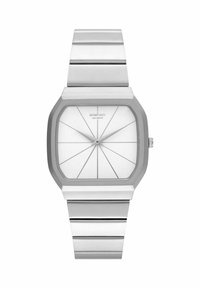 Montre en métal argenté avec un boîtier carré, cadran blanc présentant des lignes géométriques, et un bracelet en métal assorti avec un détail de maillons.