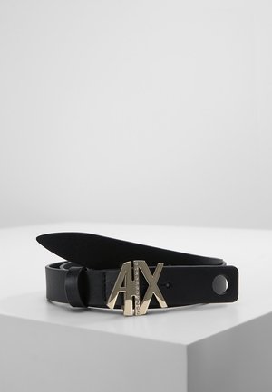 Zwarte leren riem met gouden metalen "A|X" logo gesp, versierd met kleine strassteentjes, opgerold op een witte ondergrond.