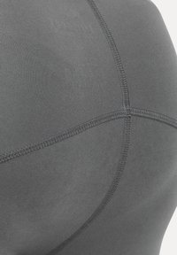 Close-up of gray fabric with intersecting flatlock seams, showing detailed stitching and smooth texture.