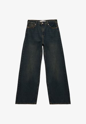 Jeans a gamba larga in denim blu scuro con vita alta, cuciture visibili, cinque tasche e rivetti in ottone. Presentano una texture leggermente sbiadita.