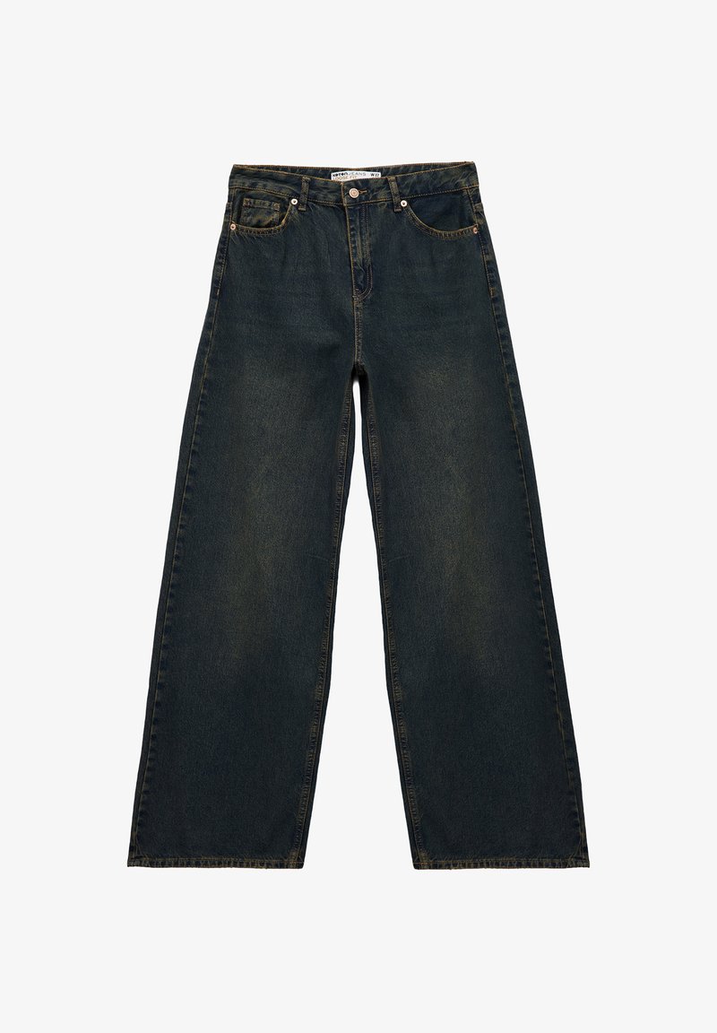 Jeans a gamba larga in denim blu scuro con vita alta, cuciture visibili, cinque tasche e rivetti in ottone. Presentano una texture leggermente sbiadita.