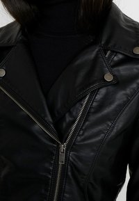 Sort lædermotorcykeljakke med lynlåslukning, trykknapper og en hakket krave. Glat tekstur med synlige syningsdetaljer.