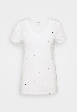 Witte V-hals T-shirt met korte mouwen en kleine verspreide multicolor hartjespatronen in zwart, rood, geel en roze.