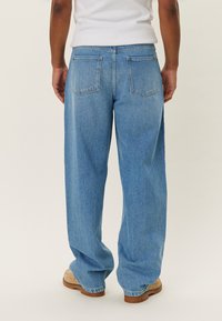 Light blue denim wide-leg jeans with a high waist, featuring two back pockets and a faded texture. Thick, sturdy fabric.