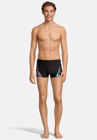 Shorts de bain noirs avec un design latéral coloré et des motifs abstraits, fabriqués à partir d'un matériau extensible, offrant un ajustement ajusté.