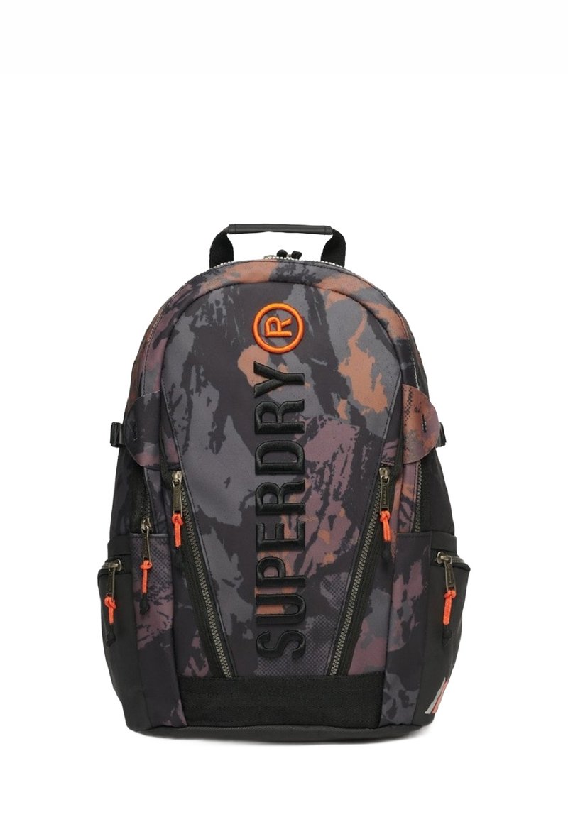 Mochila de patrón de camuflaje en gris oscuro con acentos naranjas. Presenta correas ajustables, múltiples bolsillos con cremallera y un asa en la parte superior.