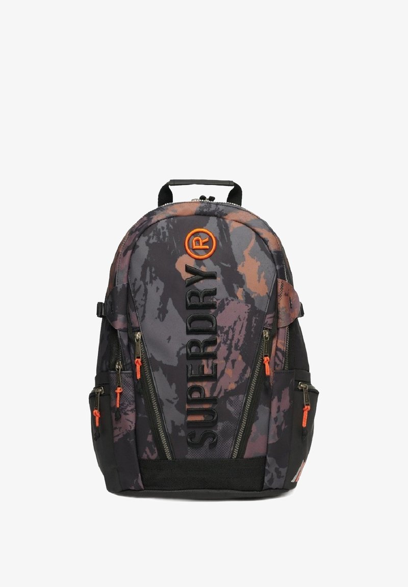 Mochila de patrón de camuflaje en gris oscuro con acentos naranjas. Presenta correas ajustables, múltiples bolsillos con cremallera y un asa en la parte superior.