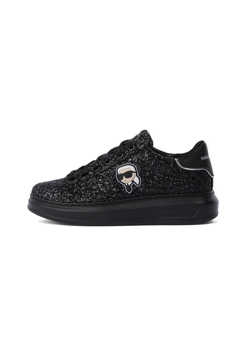 Must mustaga madal sneakers läikiva musta disainiga, nööridega ees, paksu tallaga ning väikese koomilist logoga inimesest prillidega külgedel.