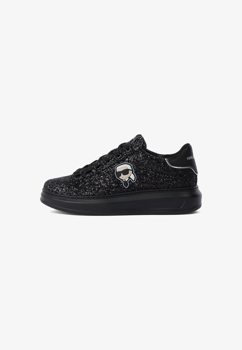 Must mustaga madal sneakers läikiva musta disainiga, nööridega ees, paksu tallaga ning väikese koomilist logoga inimesest prillidega külgedel.
