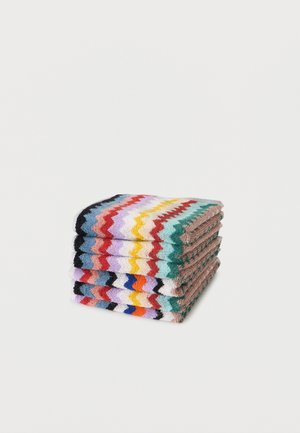 Σωρός από διπλωμένο πλεκτό ύφασμα με πολύχρωμο ζιγκ ζαγκ μοτίβο σε σειρές πάνω σε απλό λευκό φόντο.